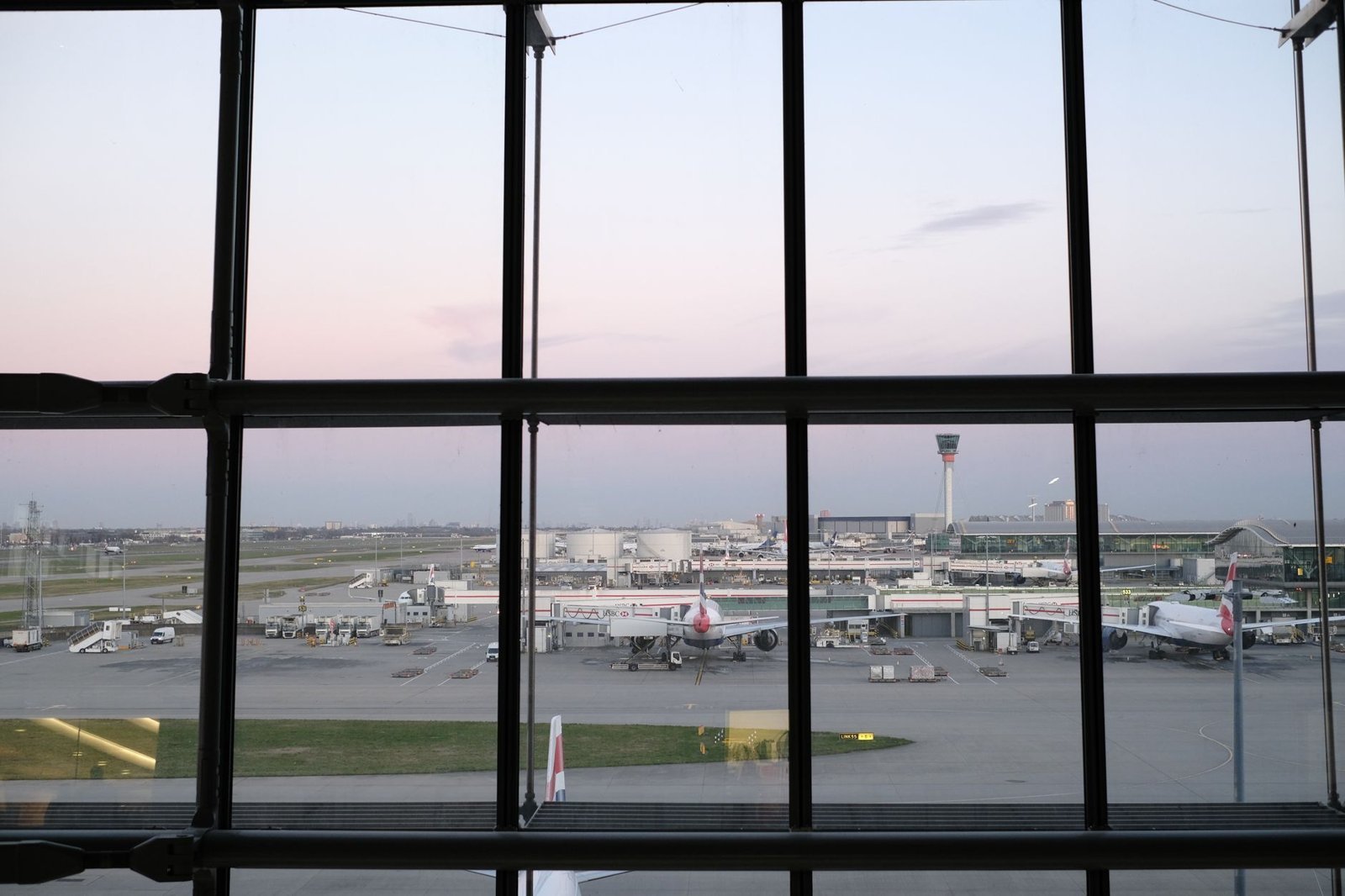 Aircraft at the gates, seen through a tall airport window at dusk